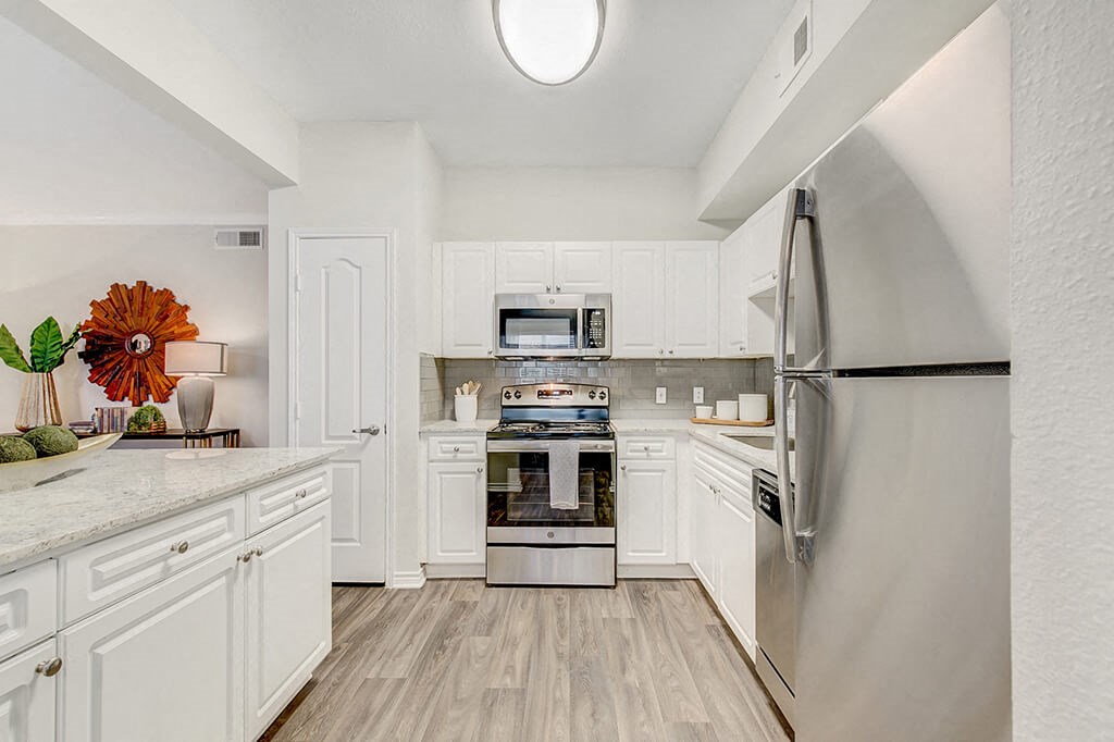 a white kitchen with stainless steel appliances and white cabinets