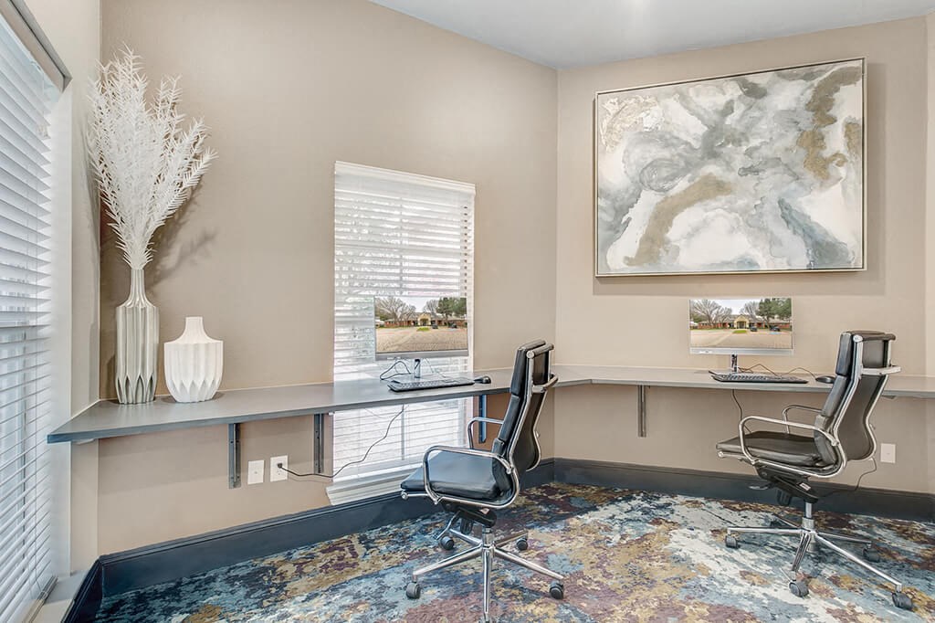 an office with two chairs and a desk with a window