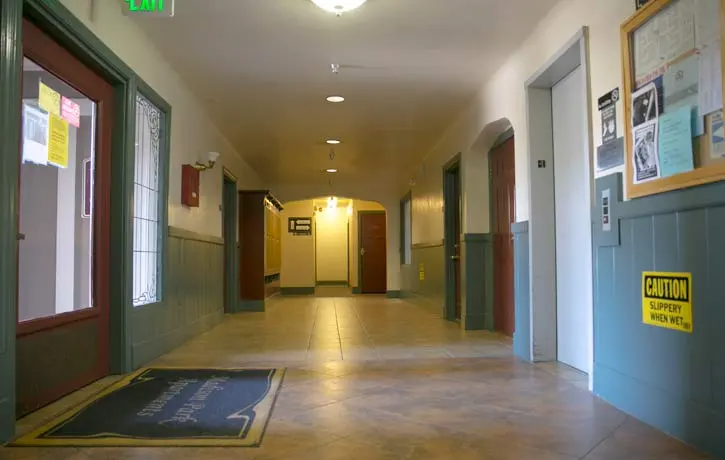 a hallway with many doors and a yellow sign on the floor