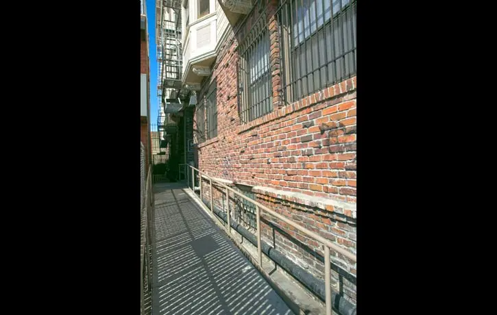 a brick wall in an alleyway next to a brick building