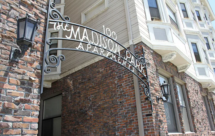 a sign for the madison park apartments in front of a brick building