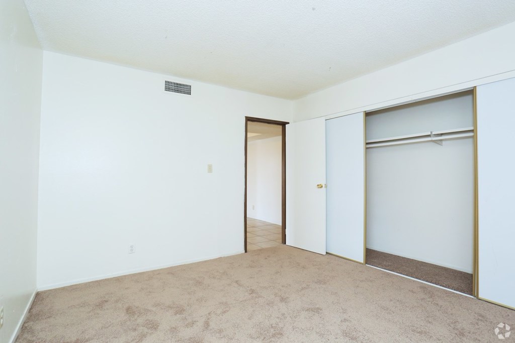 A room with a carpeted floor and a door leading to another room.