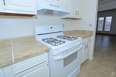 A white gas stove in a kitchen with beige tiles.