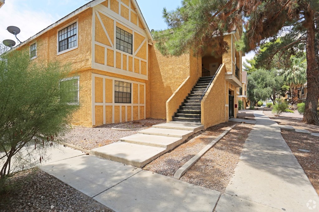 A yellow building with a staircase leading to the entrance.