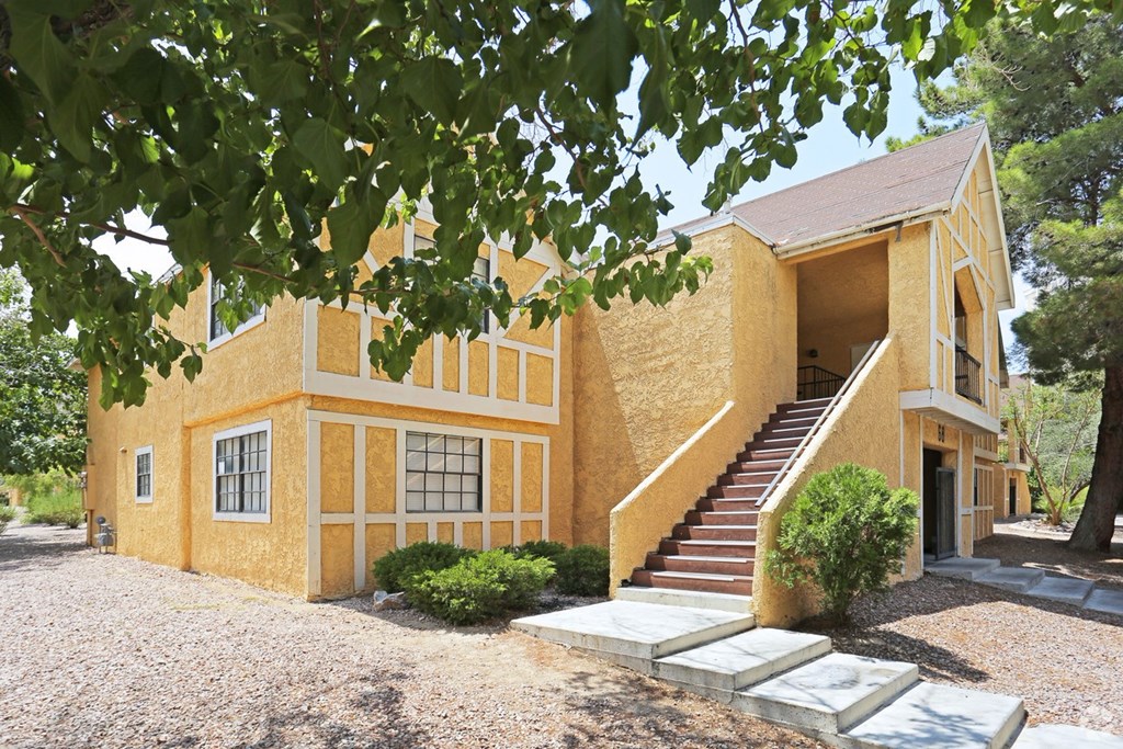 A yellow house with a staircase leading to the entrance.