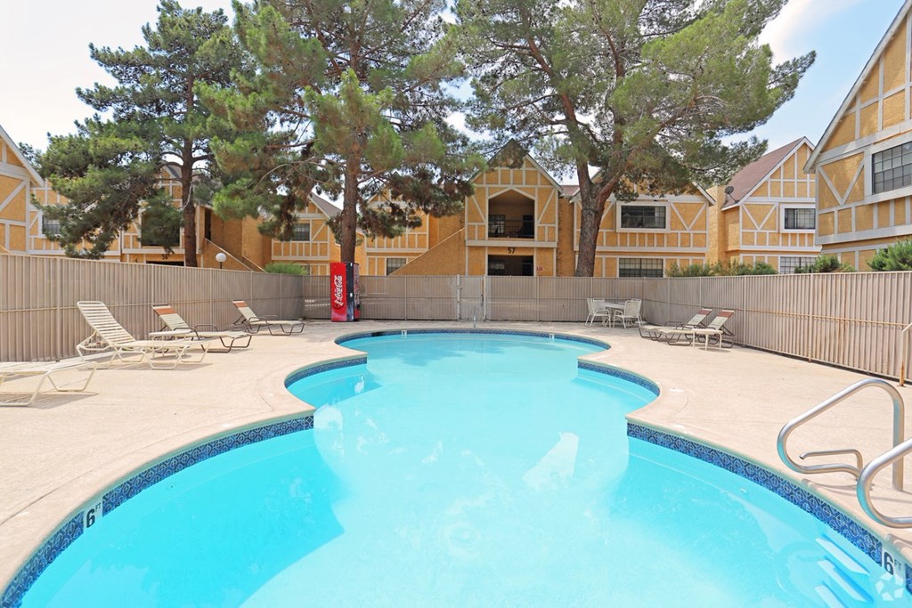 A swimming pool surrounded by a fence and chairs.