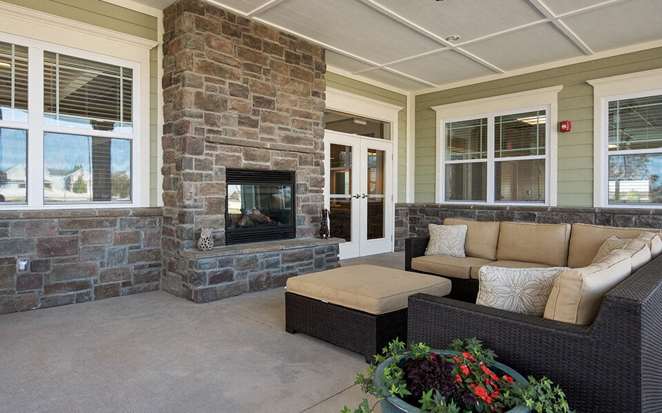 a covered porch with a stone fireplace and couches