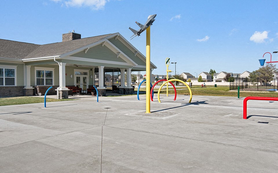 an empty parking lot with a playground and a building in the background