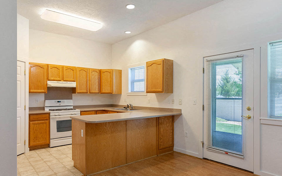 a kitchen with wooden cabinets and a window and a door