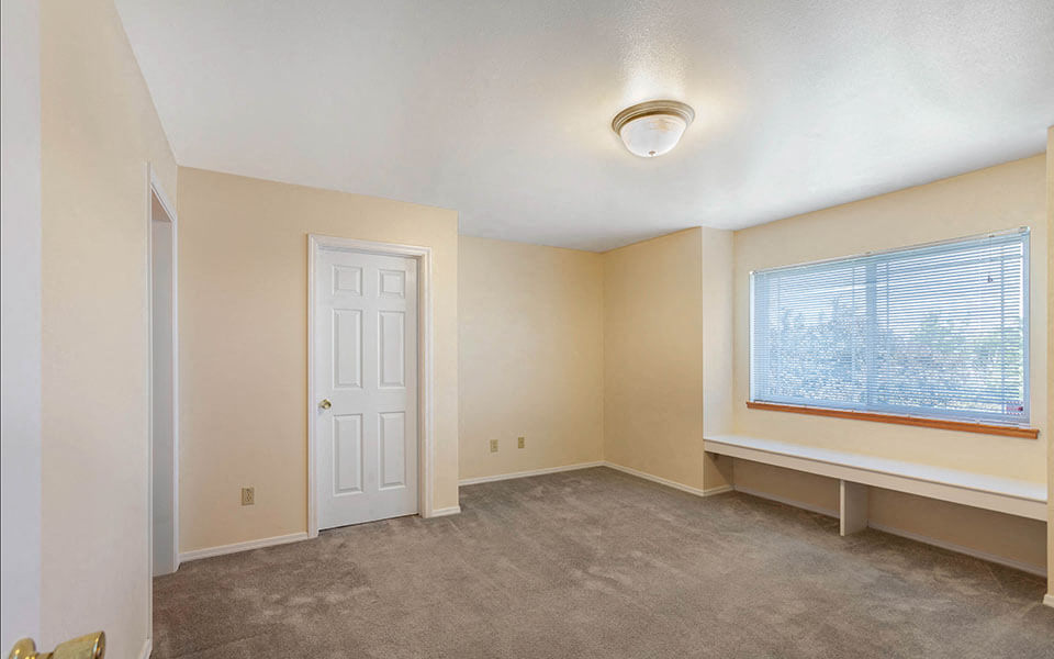 an empty living room with a window and a white door