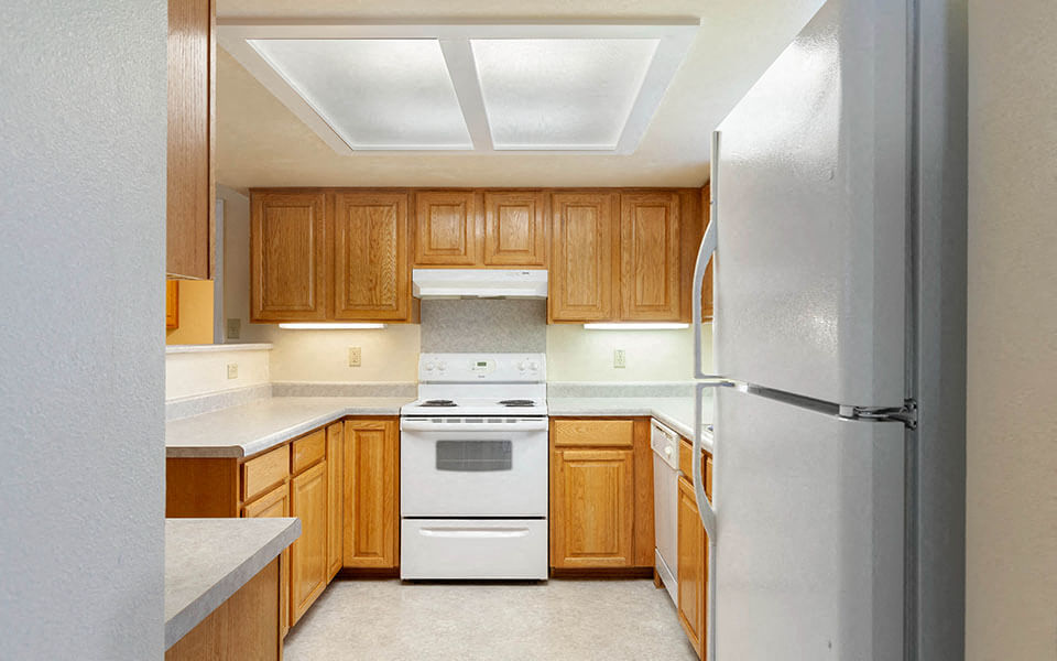 a kitchen with wooden cabinets and a white stove and refrigerator