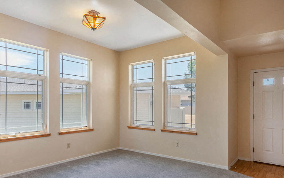 a living room with three windows and a white door