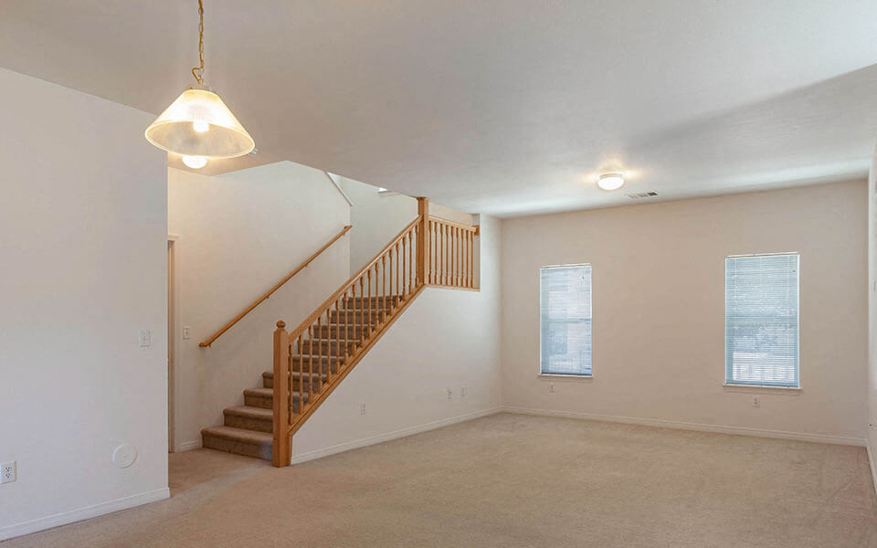 a living room with a staircase and a ceiling lamp