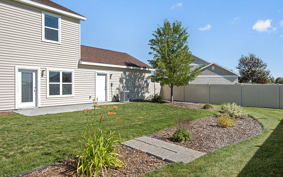 a side view of a house and a yard with grass and a tree