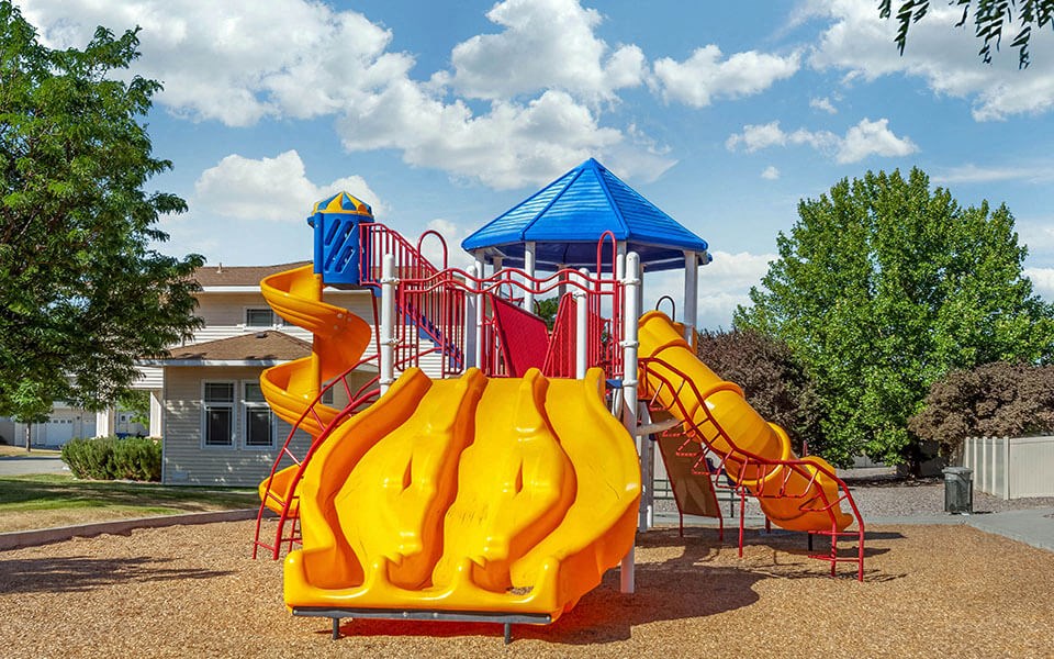 a playground with yellow slides and a blue roof