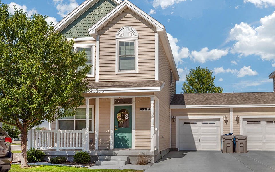the front of a house with a white porch and a green door