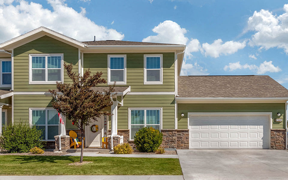 a green house with a white garage door