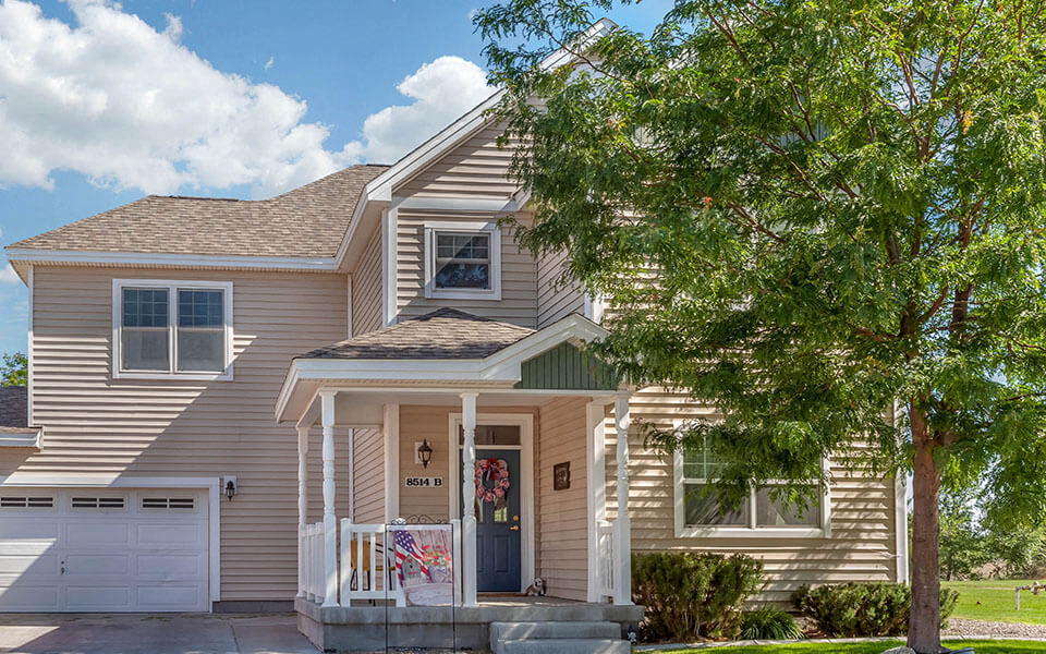 a tan house with a tree in front of it