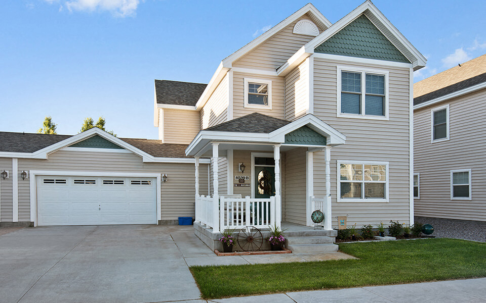a tan house with a white porch and a white garage door
