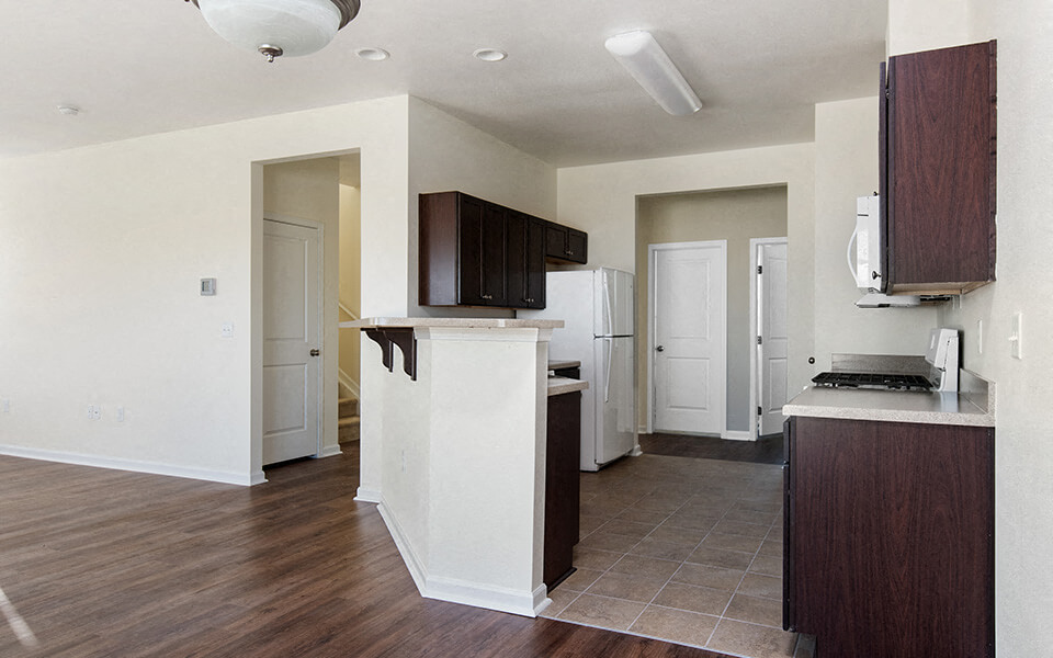an empty kitchen with wood flooring and white walls