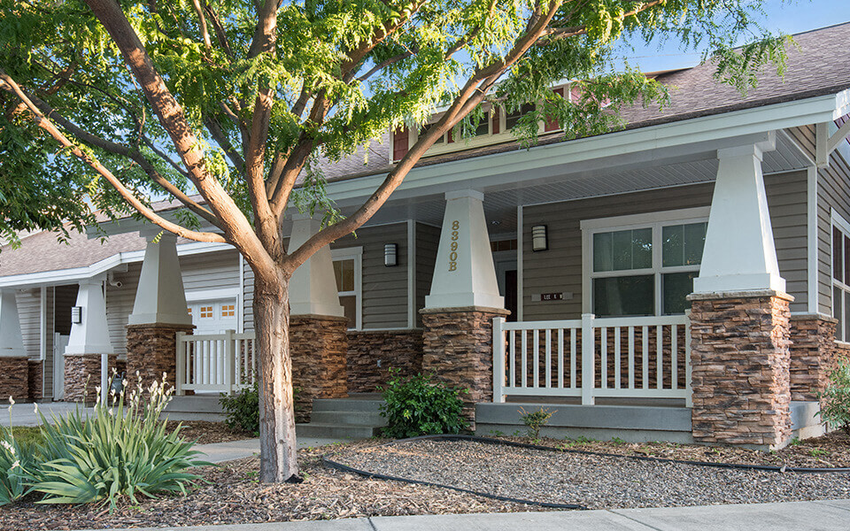 a house with a porch and a tree in front of it