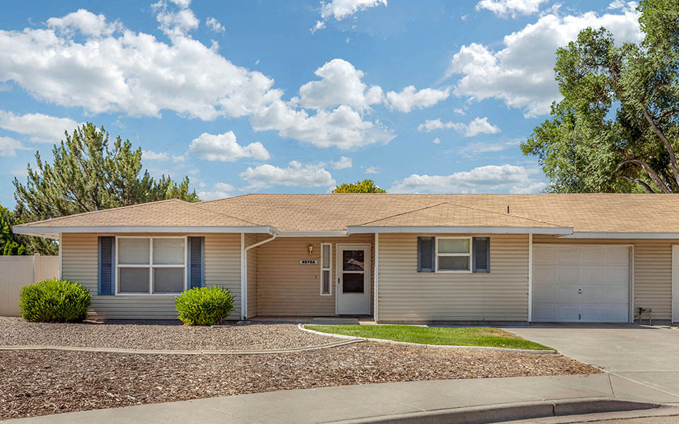 a beige house with a driveway and grass