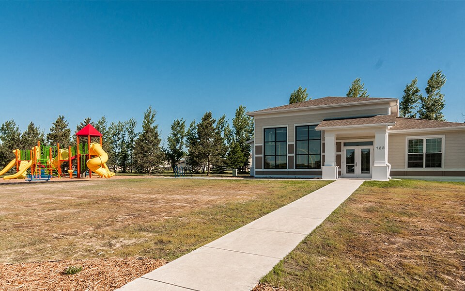 the front of our building with a playground and a sidewalk