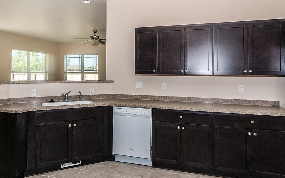 a kitchen with dark wood cabinets and a white dishwasher
