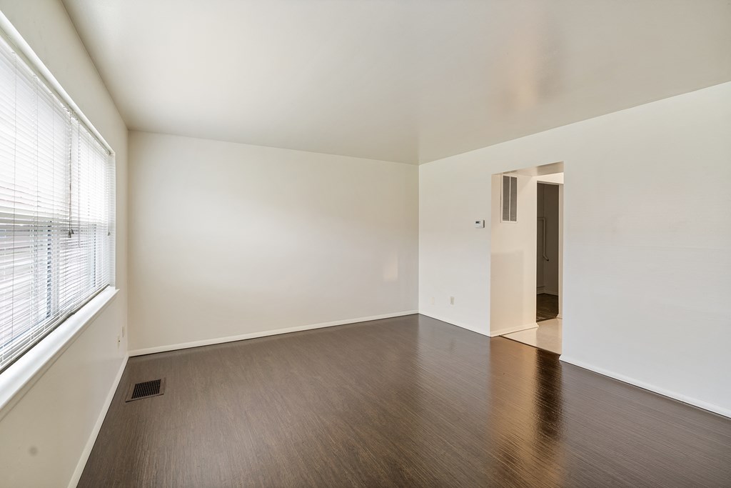 an empty living room with wood floors and a large window