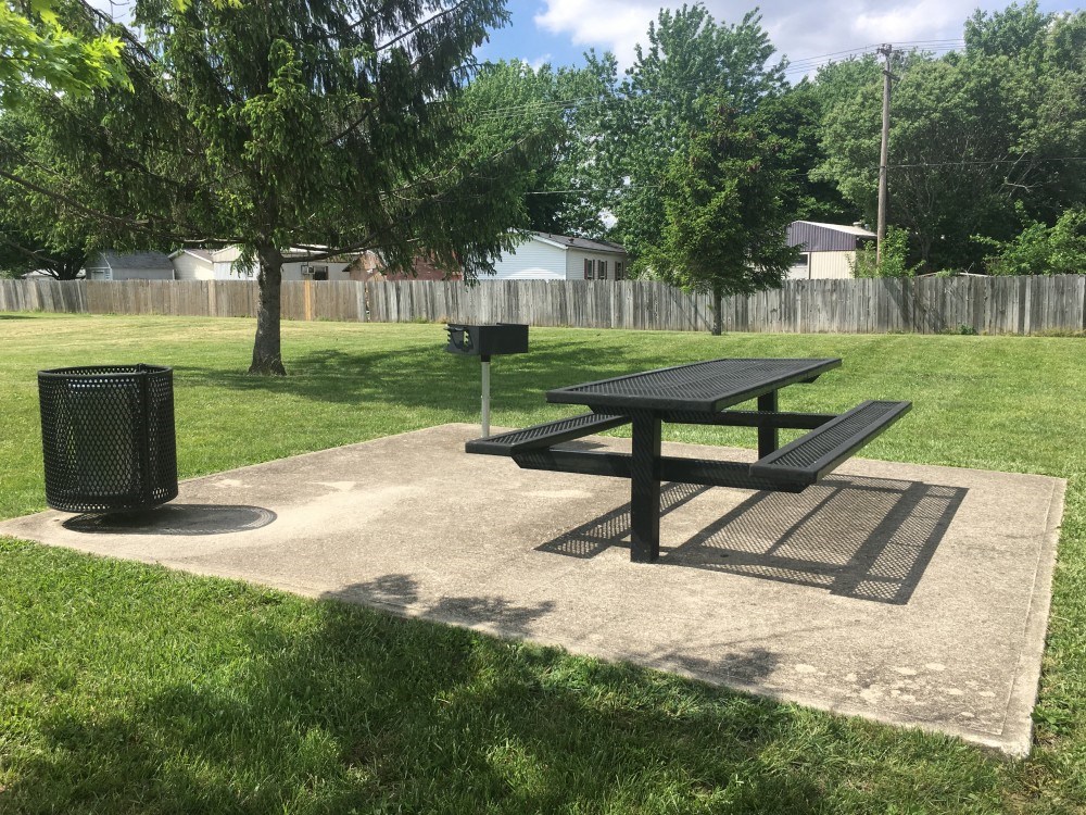 a picnic table and a trash can in a park