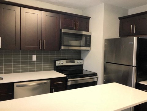 A kitchen with a white counter top and stainless steel appliances.