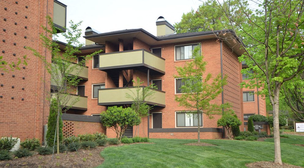 a red brick apartment building with green grass and trees
