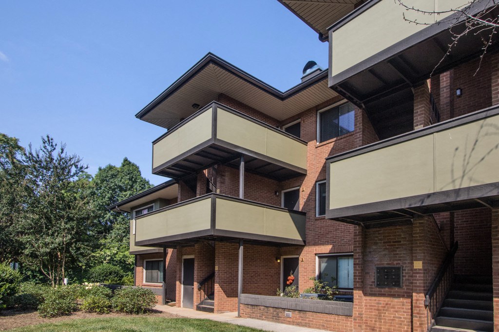 the side of a brick house with balconies and a yard