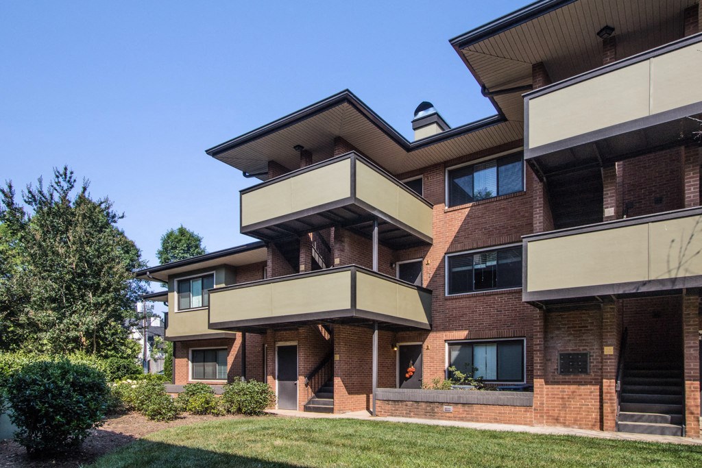 a red brick apartment building with balconies and a lawn