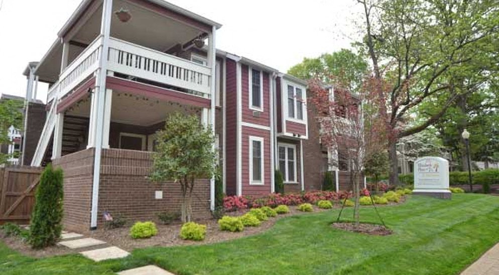 a red brick house with a porch and a lawn
