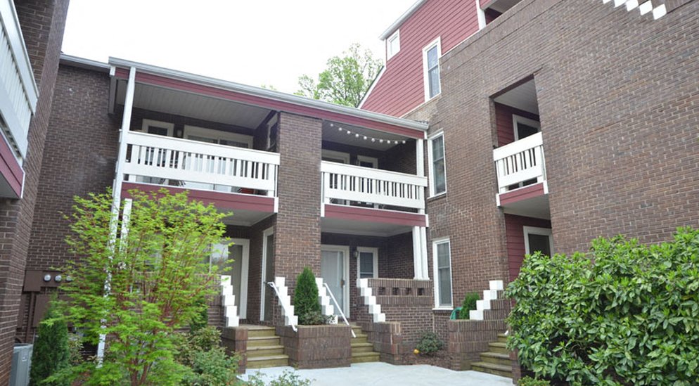 a brick house with a porch and a white balcony