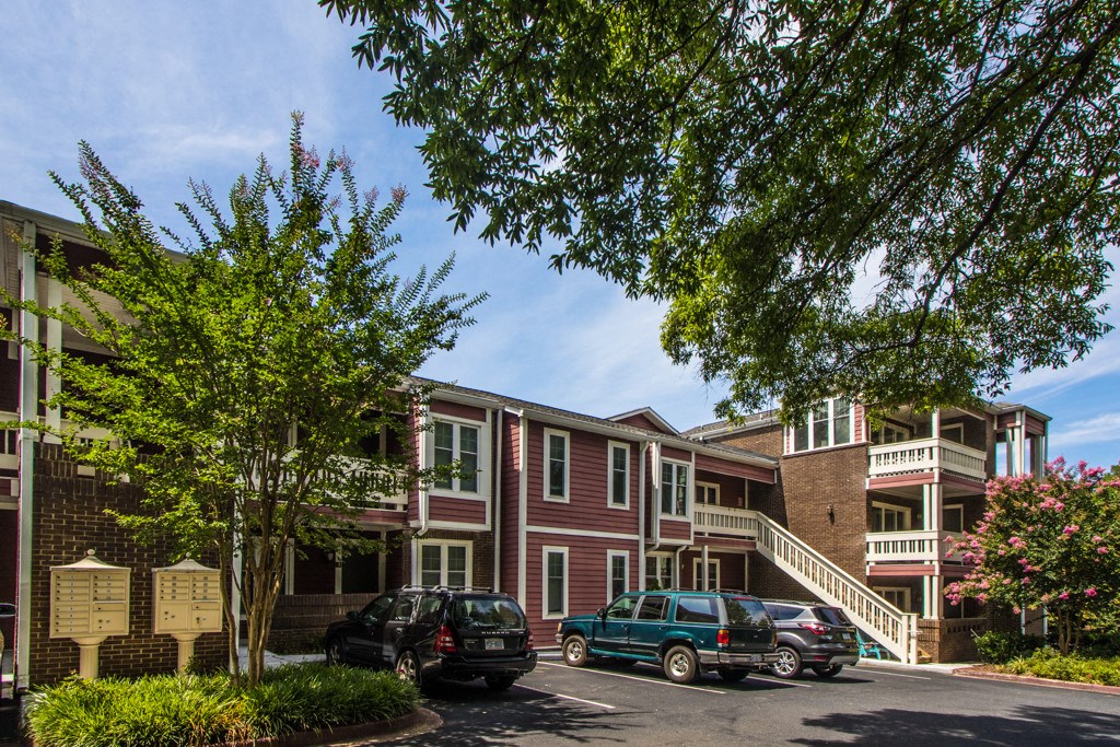 a row of red apartment buildings with cars parked in front