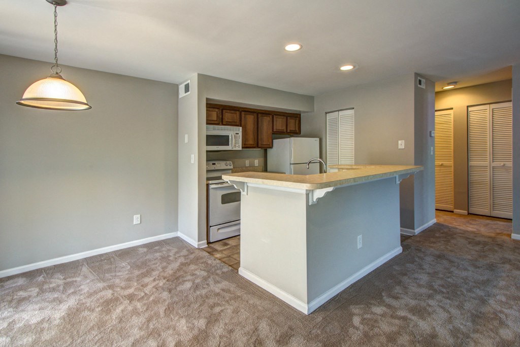 an empty living room with a kitchen with a counter top