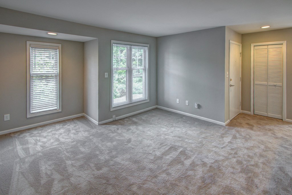 an empty living room with two windows and a door
