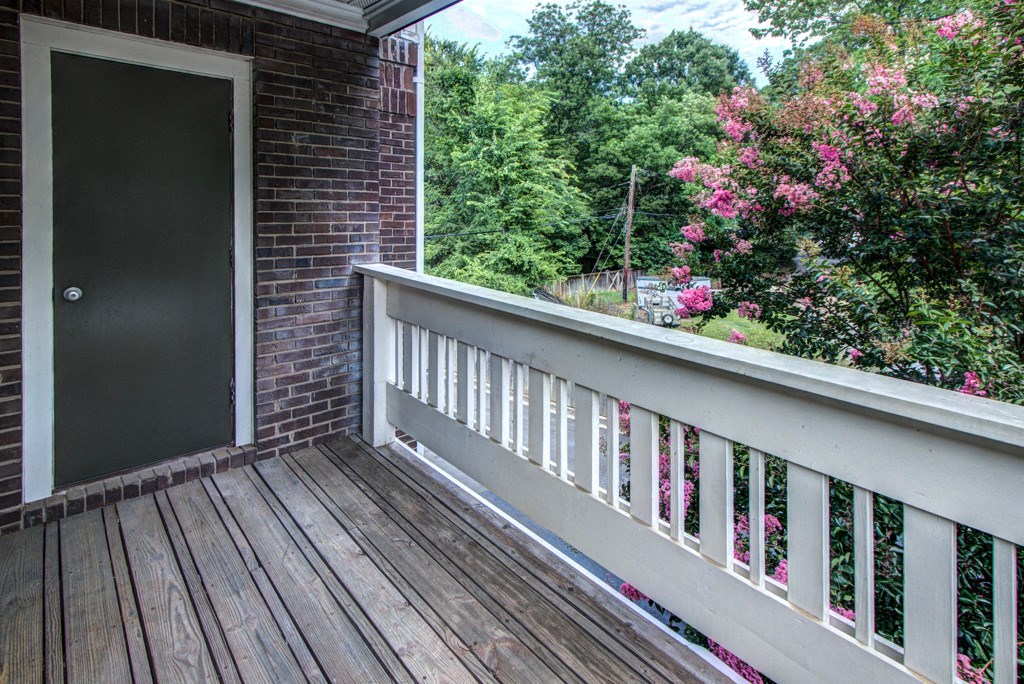 the view from the balcony of a brick house with a wooden deck and a door