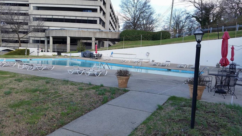 a swimming pool with chairs and umbrellas in front of a building