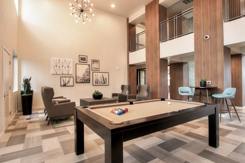 A pool table in a room with a high ceiling and a chandelier.