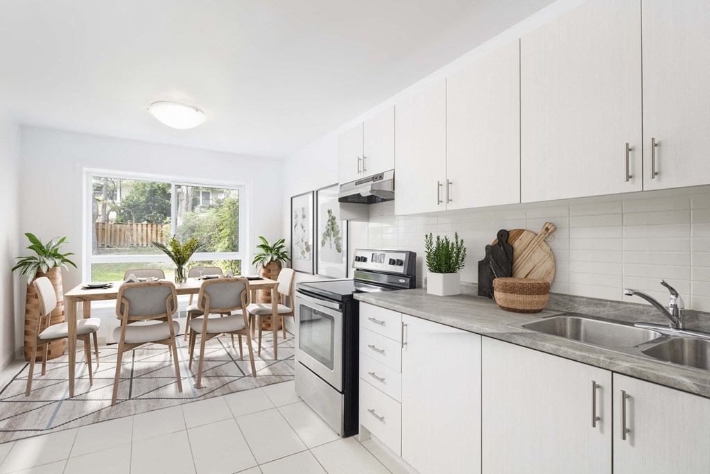 Kitchen with white cabinets overlooking a dining room staged with furniture