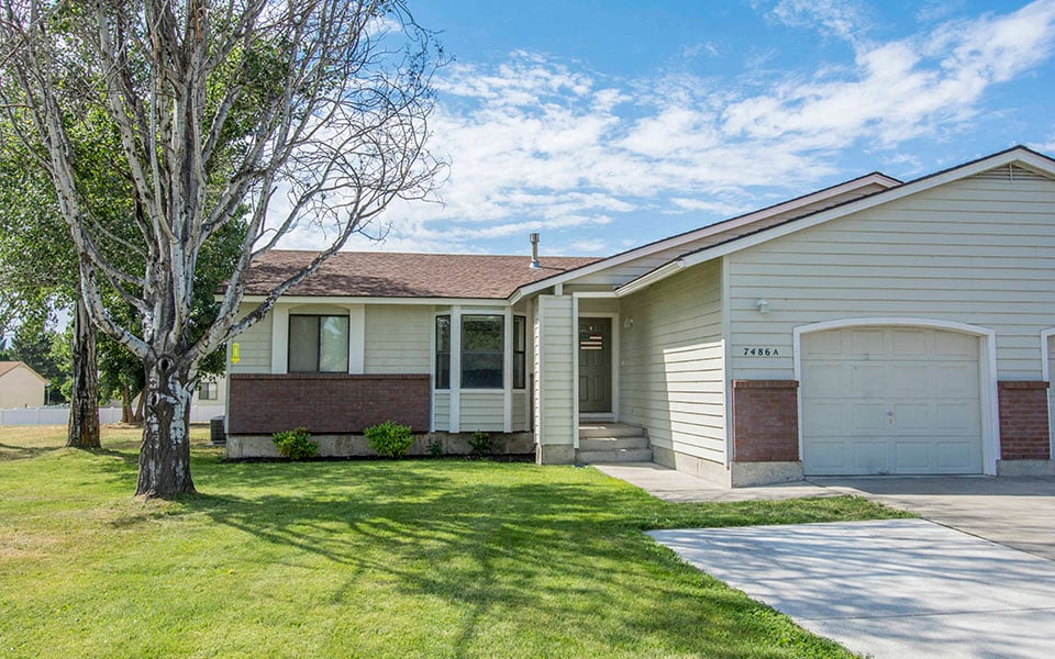 a white and brick house with a tree in the front
