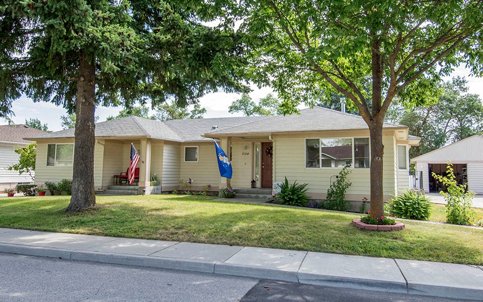 a house with a lawn and trees in front of it