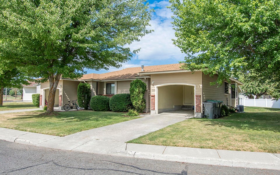 a house with a driveway and trees in front of it