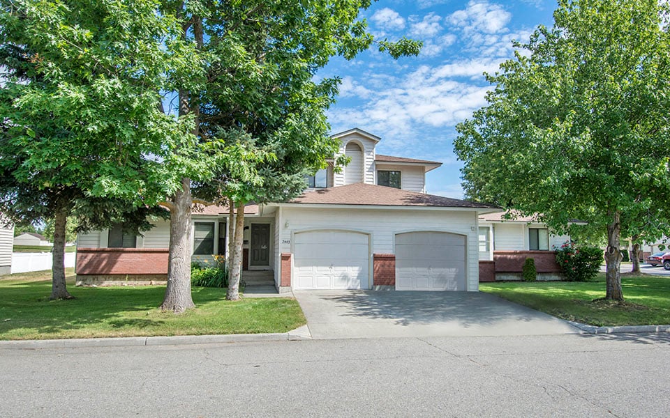 a white house with two garage doors and trees