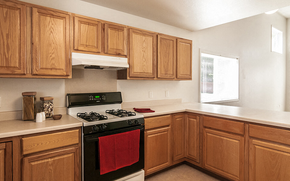 a kitchen with wooden cabinets and a stove and a window