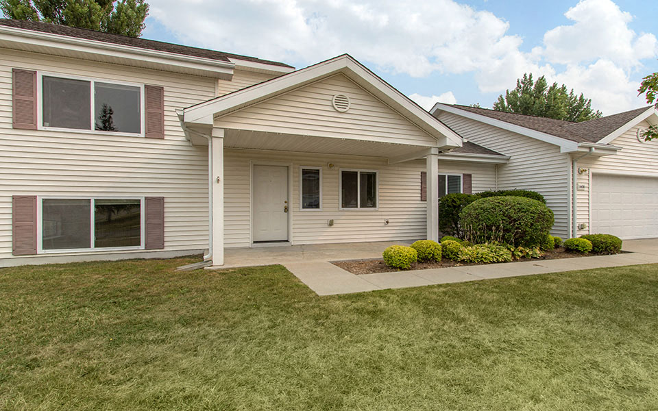the front of a white house with a driveway and grass