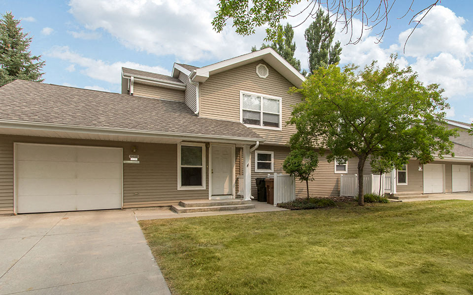 a tan house with a white garage door and a lawn